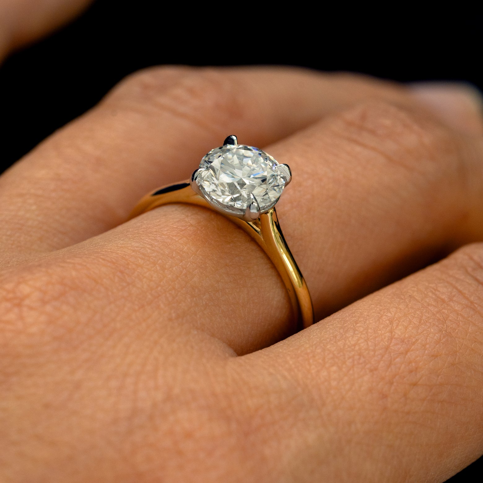 An angled view of a Round Lab Diamond Cathedral Set Ring on a model's finger to show the height of the stone