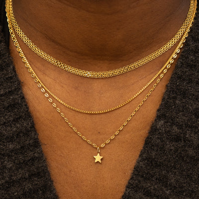 A models neck wearing a Bismark Chain, a Mini Franco Chain, and a Flat Mariner Chain with a Star Charm, layered