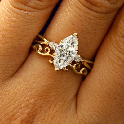 A model's fingers wearing a 14k yellow gold Marquise Lab Diamond Three Stone Ring with Band