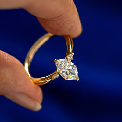 An angled view of a Marquise Lab Diamond Three Stone Ring on a model's finger to show the accent stones