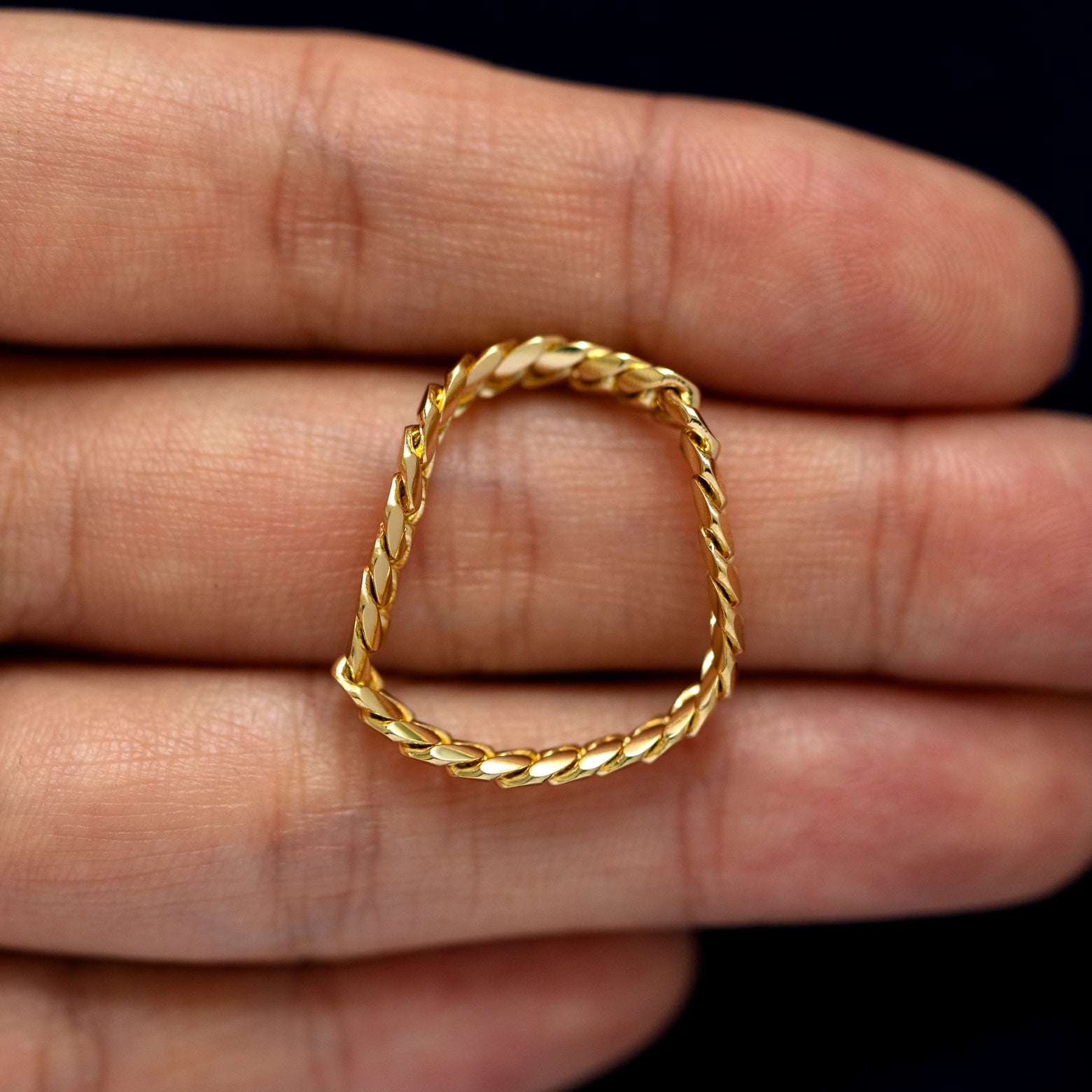 A yellow gold Medium Miami Ring laying upright in a models hand to show the thickness of the chain