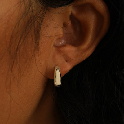 A model's ear wearing a champagne gold Medium Teardrop Huggie Hoop and a Small Teardrop Huggie Hoop in two piercings