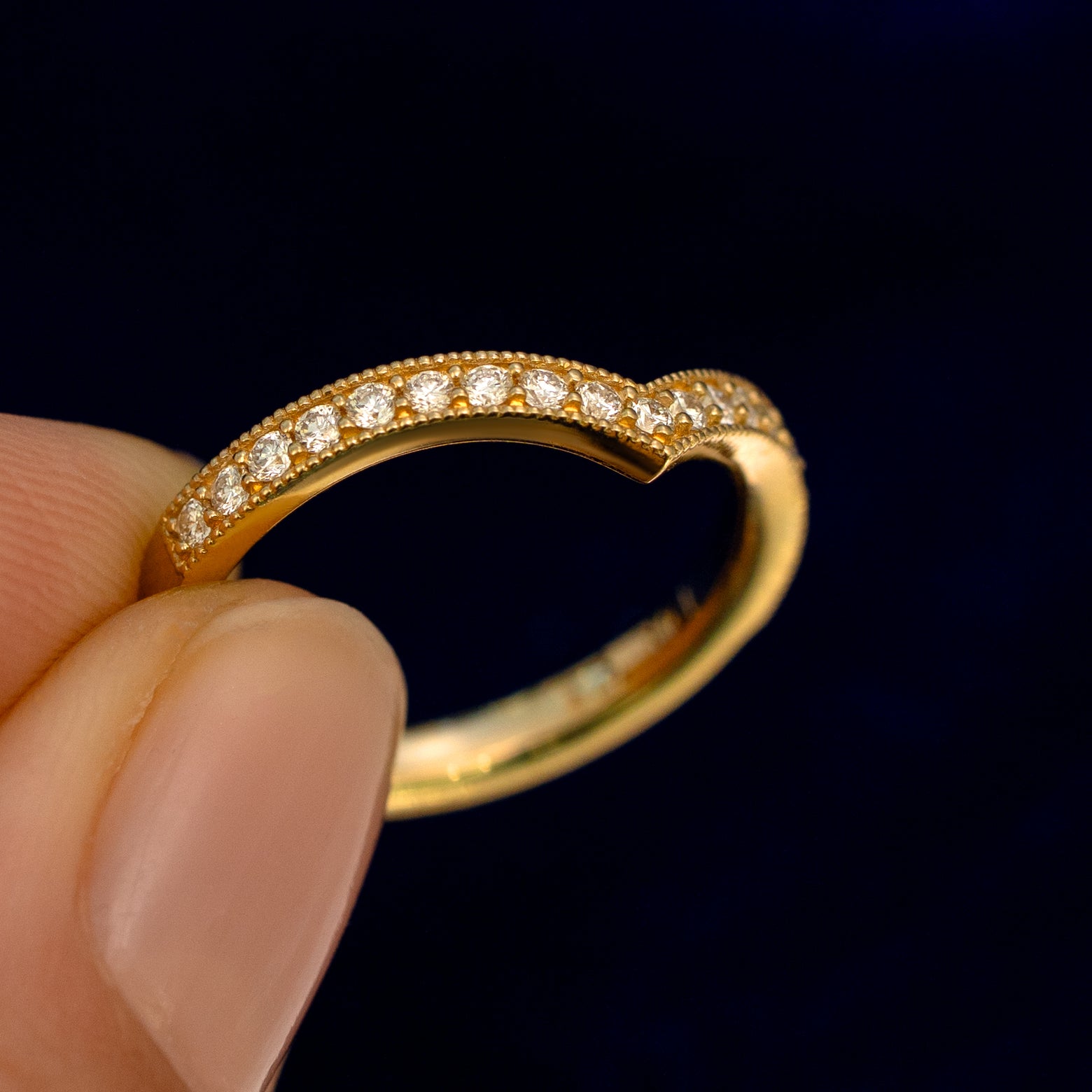 A model holding a Milgrain Pave Diamond Chevron Band up to show the details of the design and the inside of the ring