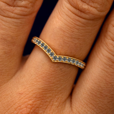 Close up view of a model's fingers wearing a 14k yellow gold Milgrain Pave Salt and Pepper Diamond Chevron Band