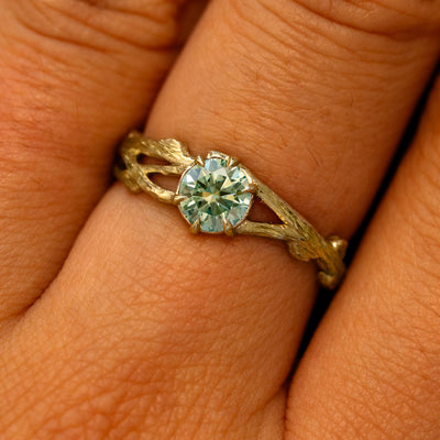 Close up view of a model's fingers wearing a 14k yellow gold Mint Moissanite Branches Ring