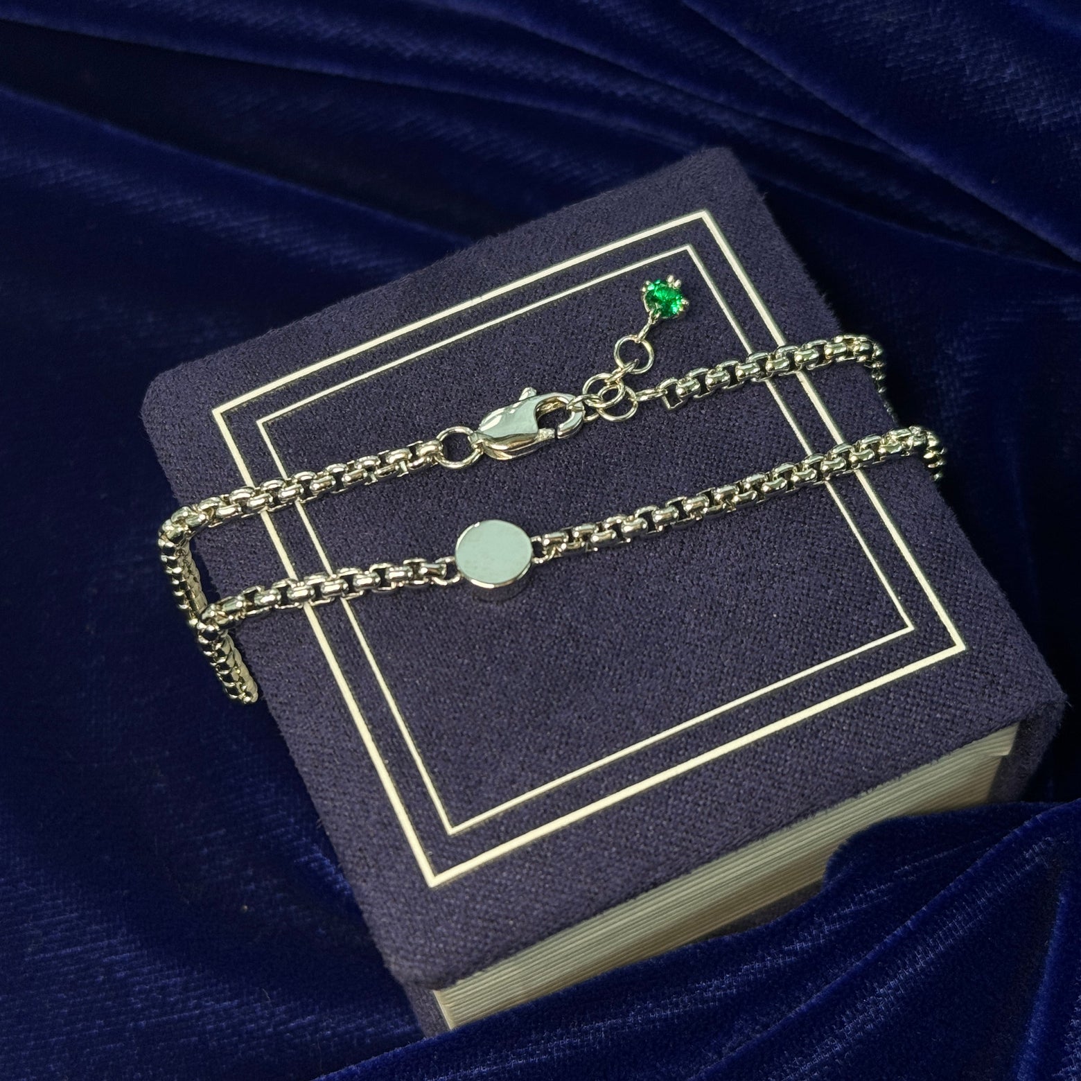 A photo of mirror circle necklace with sand inside resting on a blue background 
