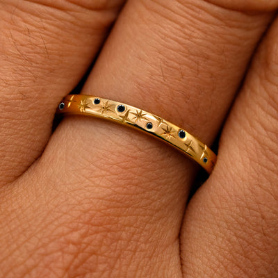 Close up view of a model's fingers wearing a 14k yellow gold Mixed Black Diamond Stars Band