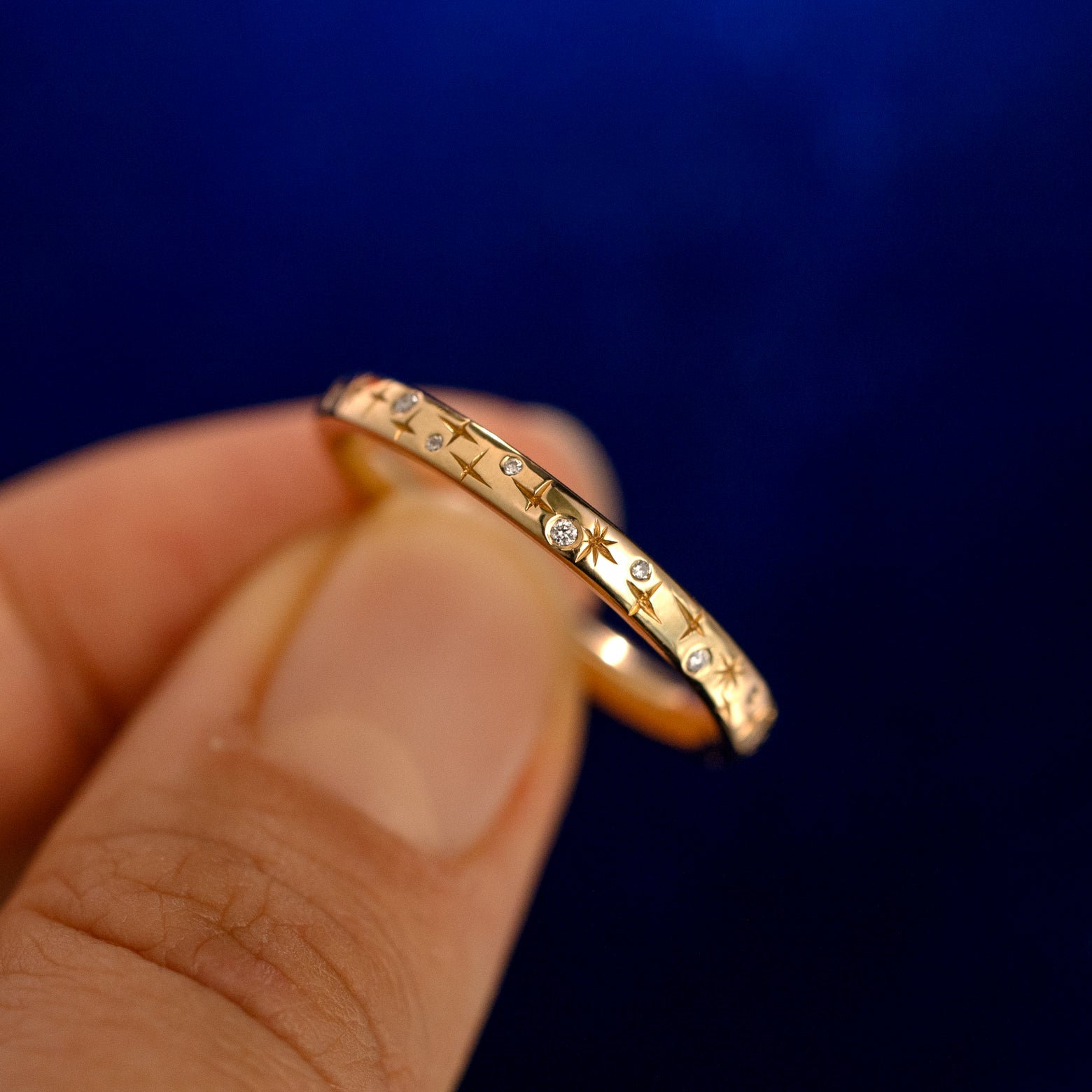A model holding a Mixed Diamond Stars Band up to show the details of the design and the inside of the ring