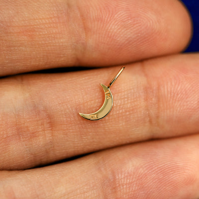 A 14k gold Moon Charm for chain resting in a model's palm to show the underside of the charm