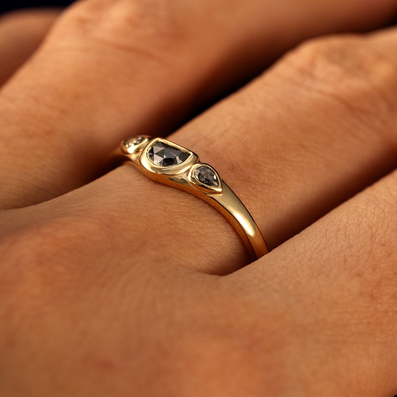 Side view of a solid 14 karat gold Moon Cut Salt and Pepper Diamond Ring on a model's finger