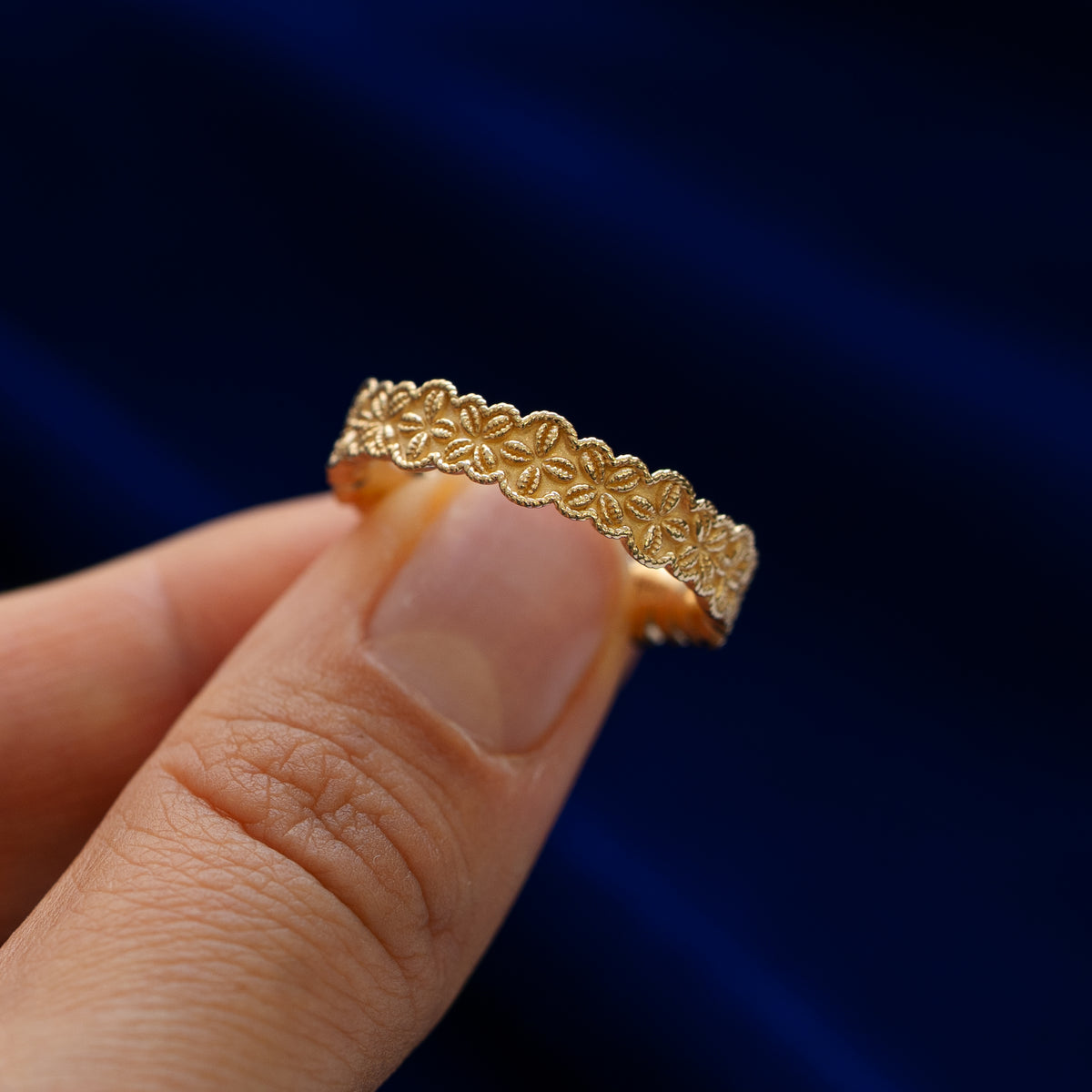 A model holding a cowrie shell flower and rope band between two fingers to show engraved pattern details
