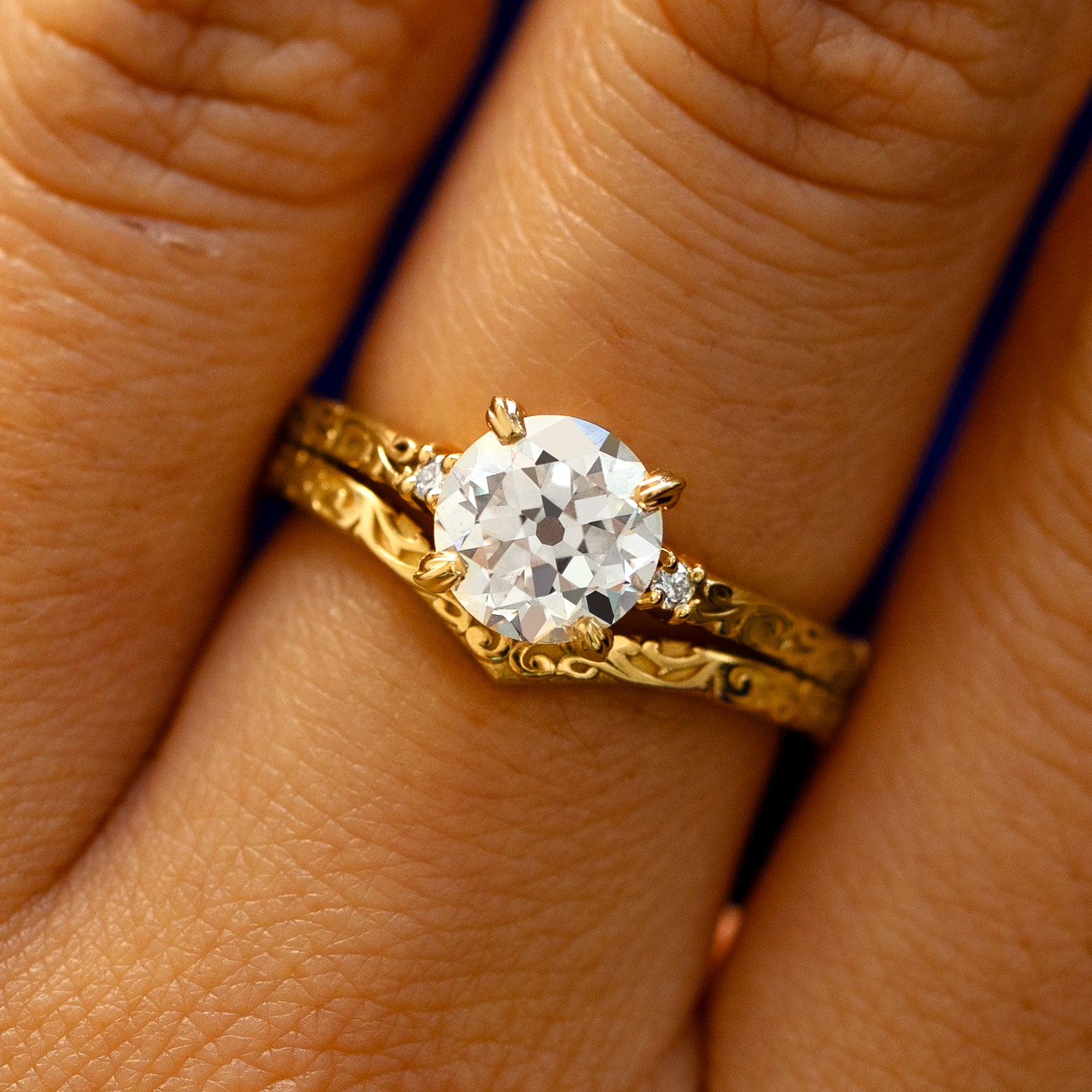 A model's fingers wearing a 14k yellow gold Old Mine Cut Lab Diamond Filigree Ring with Filigree Chevron Band