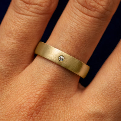 Close up view of a model's fingers wearing a 14k yellow gold Mix Matte Band with one diamond