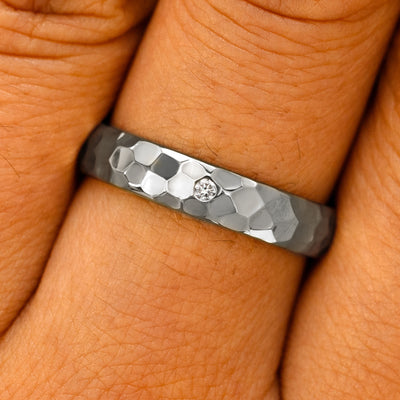 Close up view of a model's fingers wearing a Platinum Curvy Hammered Band with one diamond