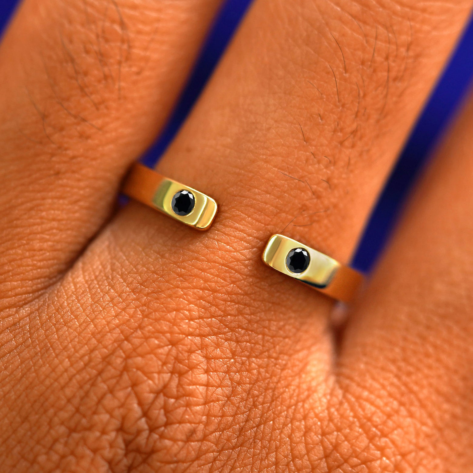 Close up view of a model's fingers wearing a 14k yellow gold Open Industrial Black Diamond Band
