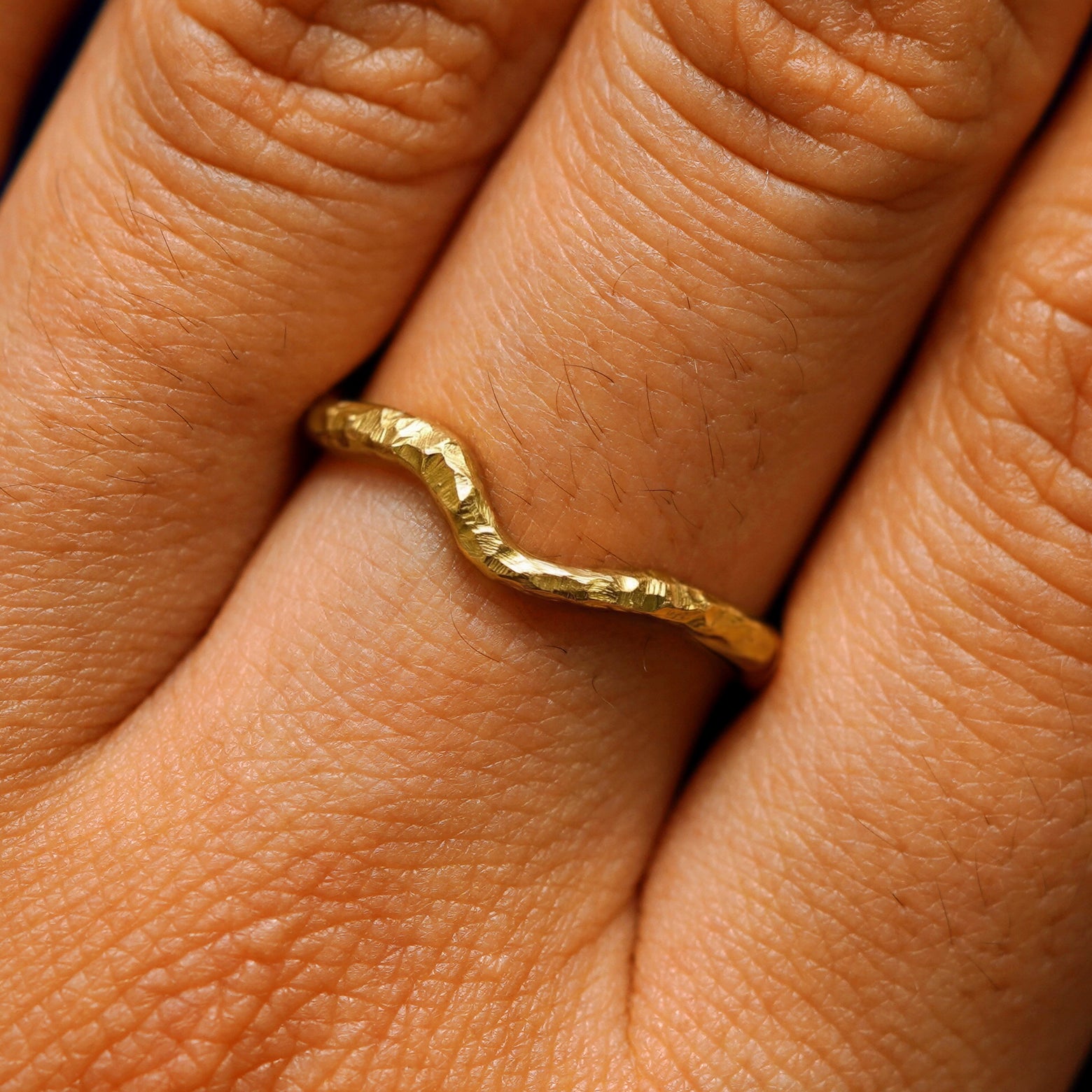 Close up view of a model's hand wearing a organic thin liquid band