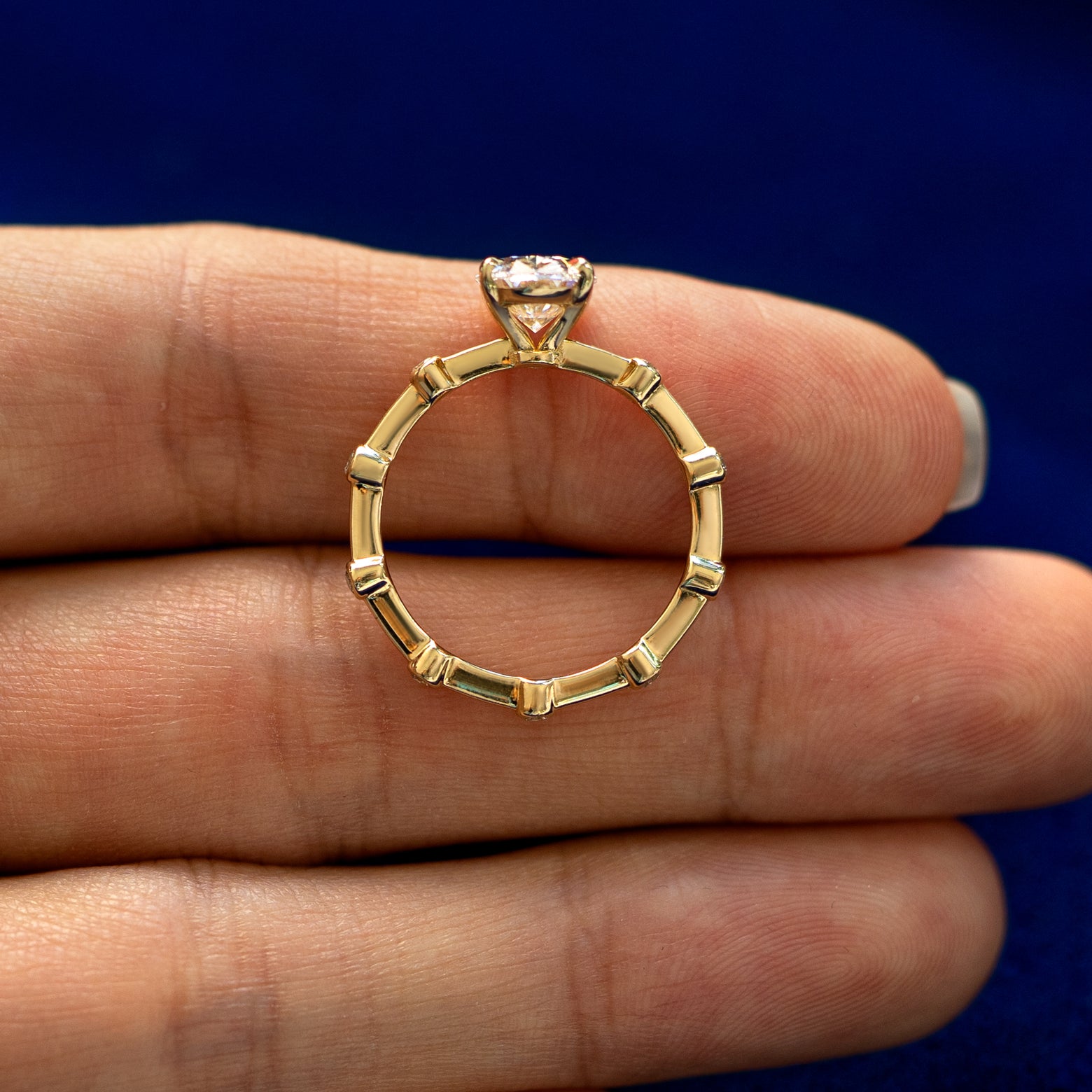 A yellow gold Oval Lab Diamond Bubble Ring in a model's hand showing the thickness of the band