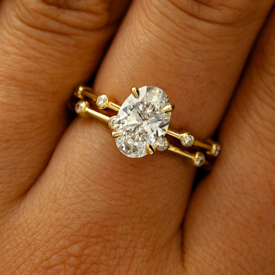 A model's fingers wearing a 14k yellow gold Oval Lab Diamond Bubble Ring stacked with A Mini Bubble Band