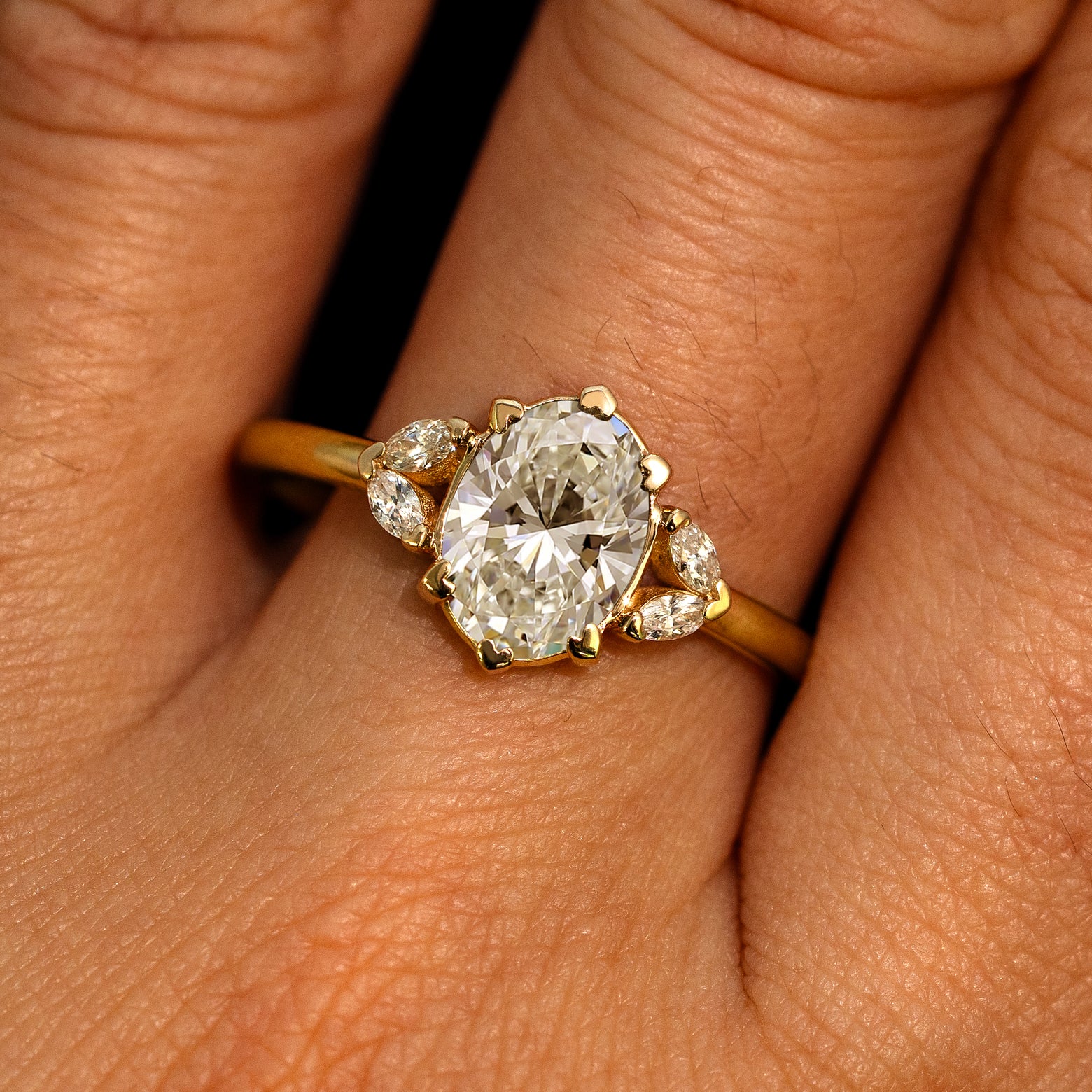A model's hand wearing a 14k yellow gold Oval Lab Clear Diamond Heart Prong Ring