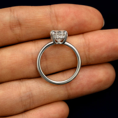 A Oval Moissanite Halo Ring in a model's hand showing the thickness of the band and the height of the ring