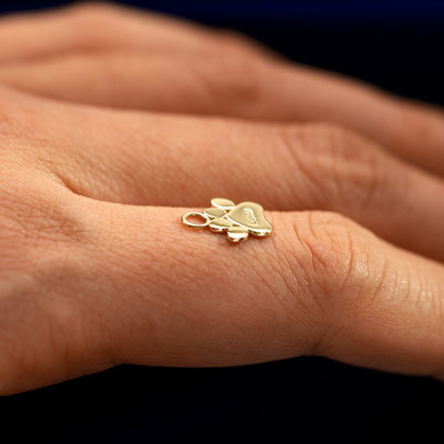 Side view of a for earring paw charm resting on a models finger to show the thickness of the charm