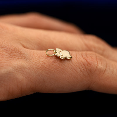 Side view of a for chain paw charm resting on a models finger to show the thickness of the charm