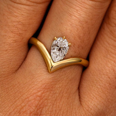 A model's hand wearing a 14k yellow gold Pear Clear Diamond Chevron Ring