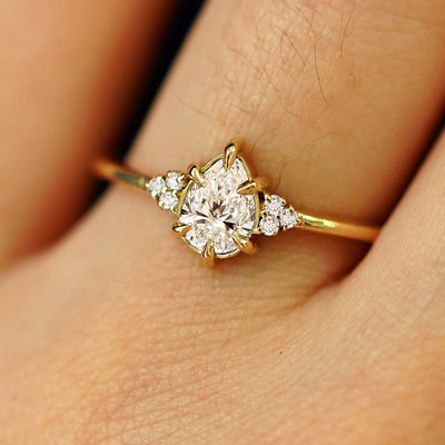Close up view of a model's hand wearing a solid yellow gold Pear Lab Diamond Cluster Ring