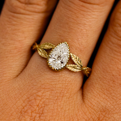 Close up view of a model's fingers wearing a 14k yellow gold Pear Lab Clear Diamond Leaves Ring