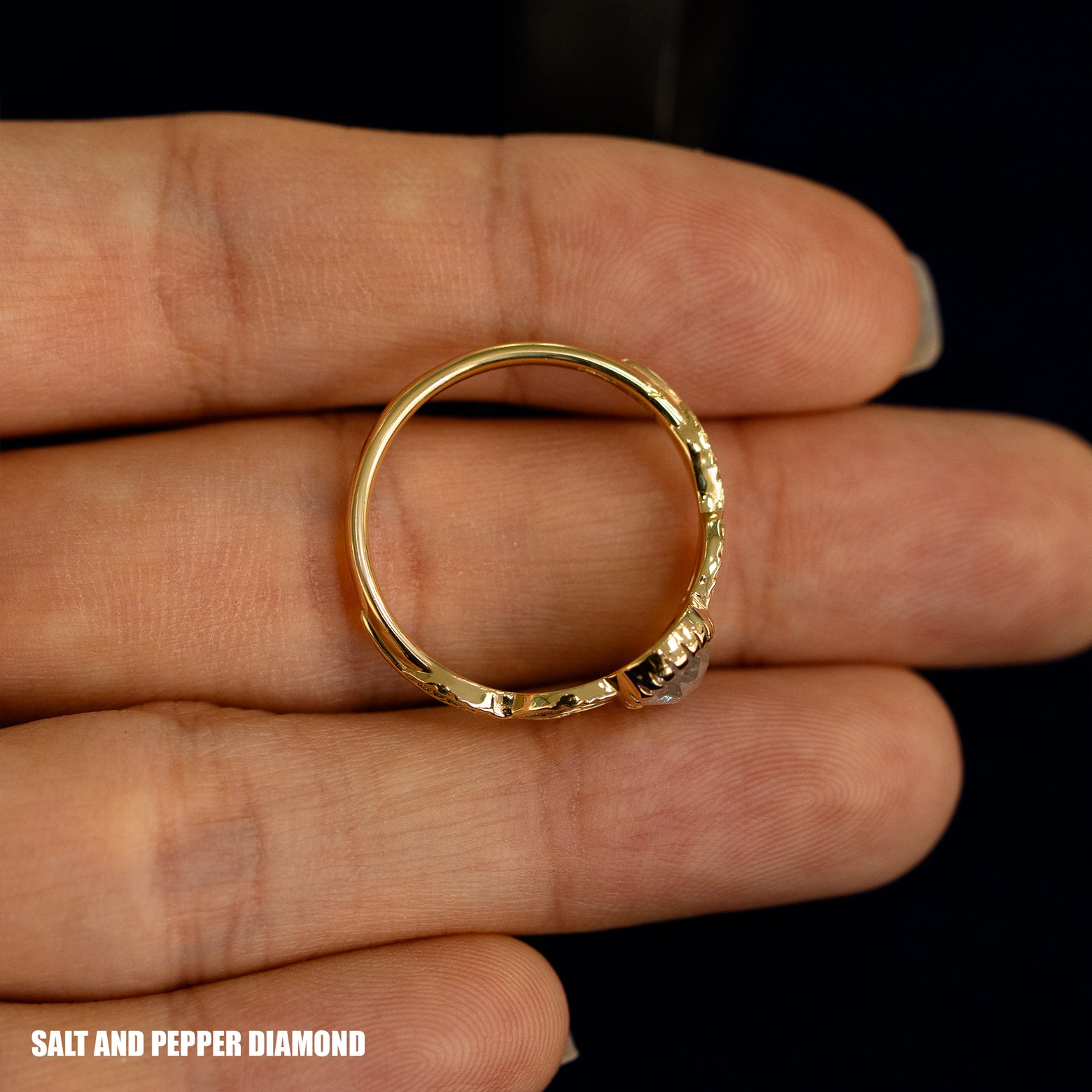 A yellow gold Pear Salt and Pepper Diamond Leaves Ring in a model's hand showing the thickness of the band