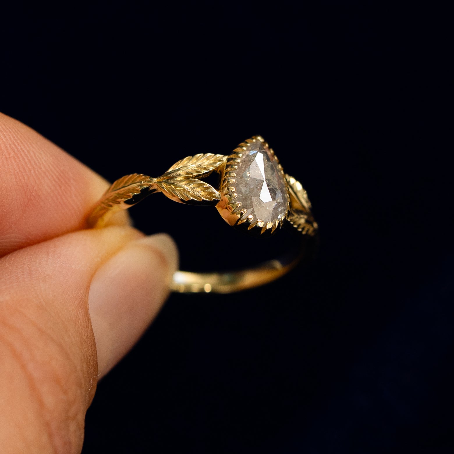 A model holding a Pear Salt and Pepper Diamond Leaves Ring tilted to show the inside of the ring