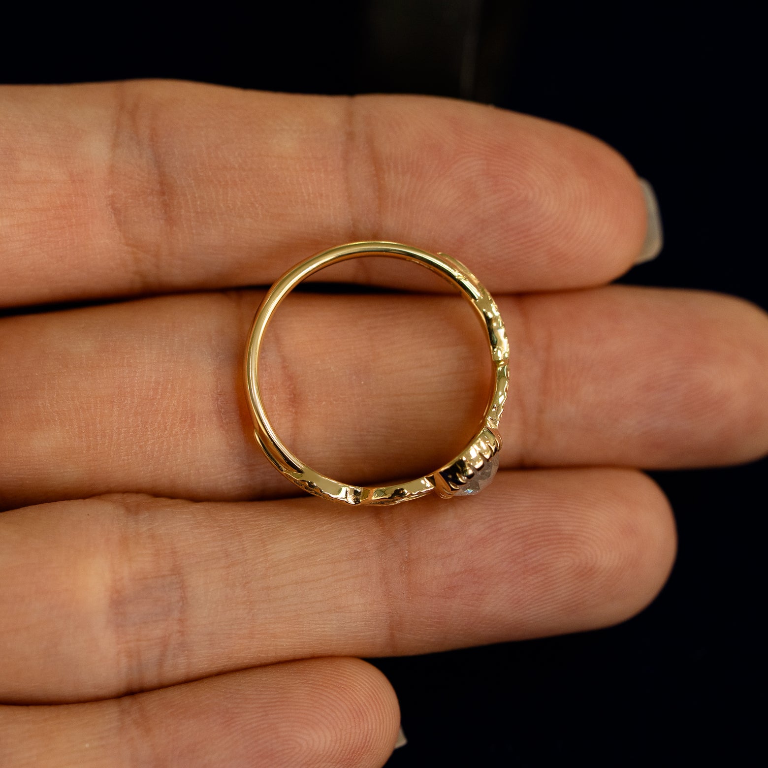 A yellow gold Pear Salt and Pepper Diamond Leaves Ring in a model's hand showing the thickness of the band