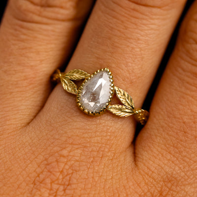Close up view of a model's fingers wearing a 14k yellow gold Pear Salt and Pepper Diamond Leaves Ring