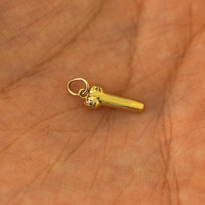 Another angle of a 14k yellow gold penis charm in the palm of a models hand
