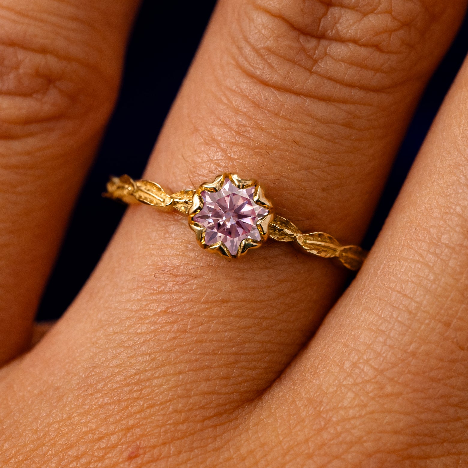 A solid 14k yellow gold Pink Moissanite Leaf Ring on a model's finger