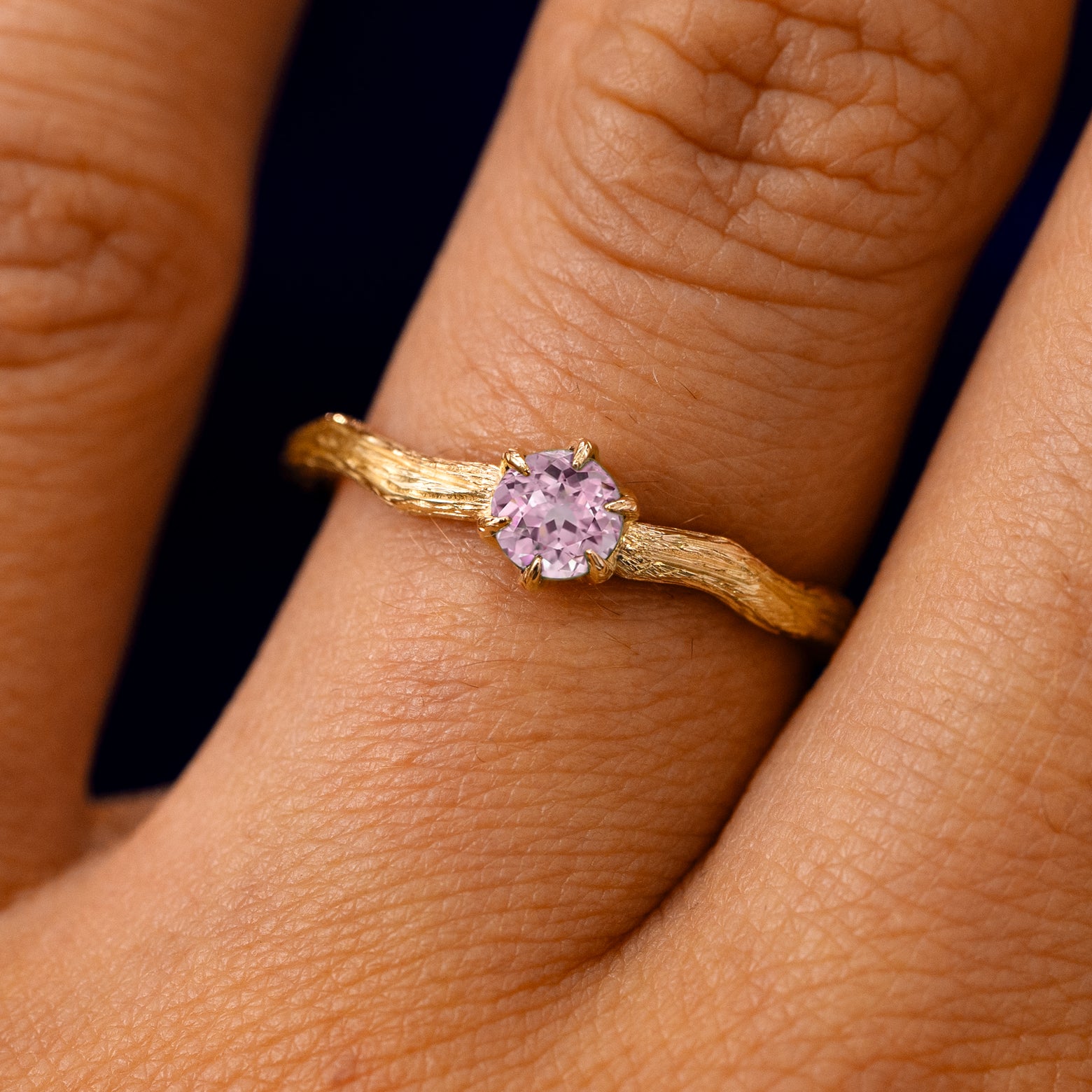 A solid 14k yellow gold Pink Sapphire Waved Branch Ring on a model's finger