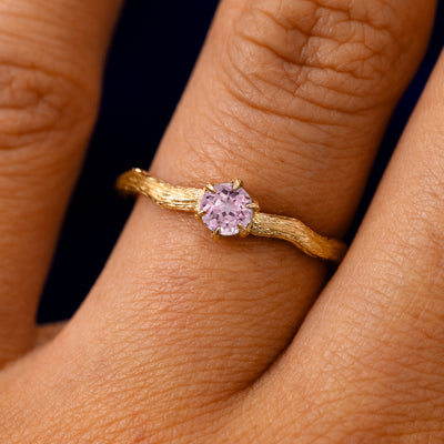 A solid 14k yellow gold Pink Sapphire Waved Branch Ring on a model's finger