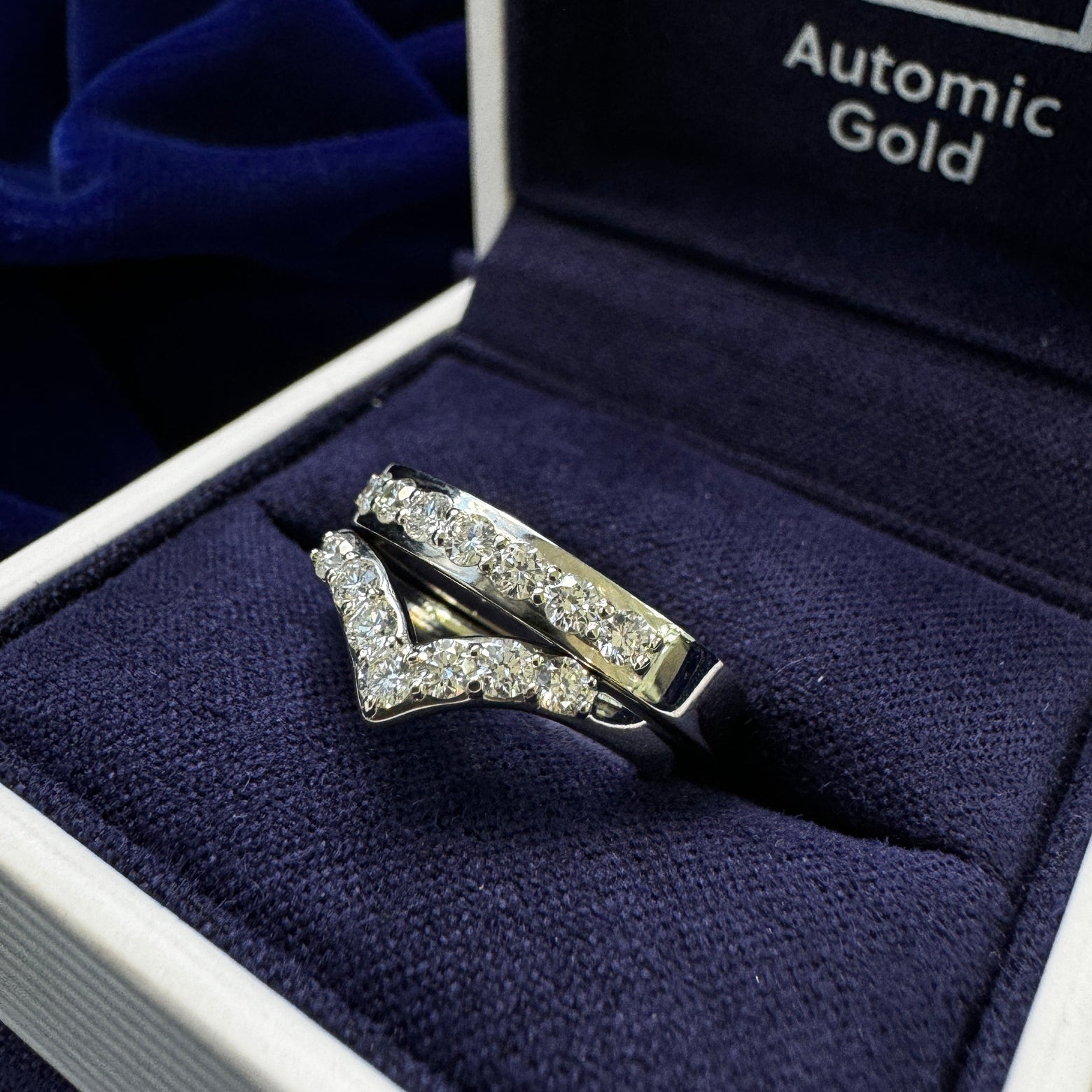 Two platinum round diamond rings one of each on chevron nesting band and one is on curvy mirror band