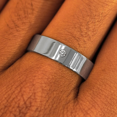 Close up view of a model's fingers wearing a 6mm Platinum Industrial Mirror Band with one diamond