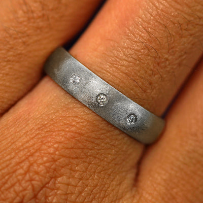 Close up view of a model's fingers wearing a 4mm 925 silver Curvy Matte Band with three diamonds