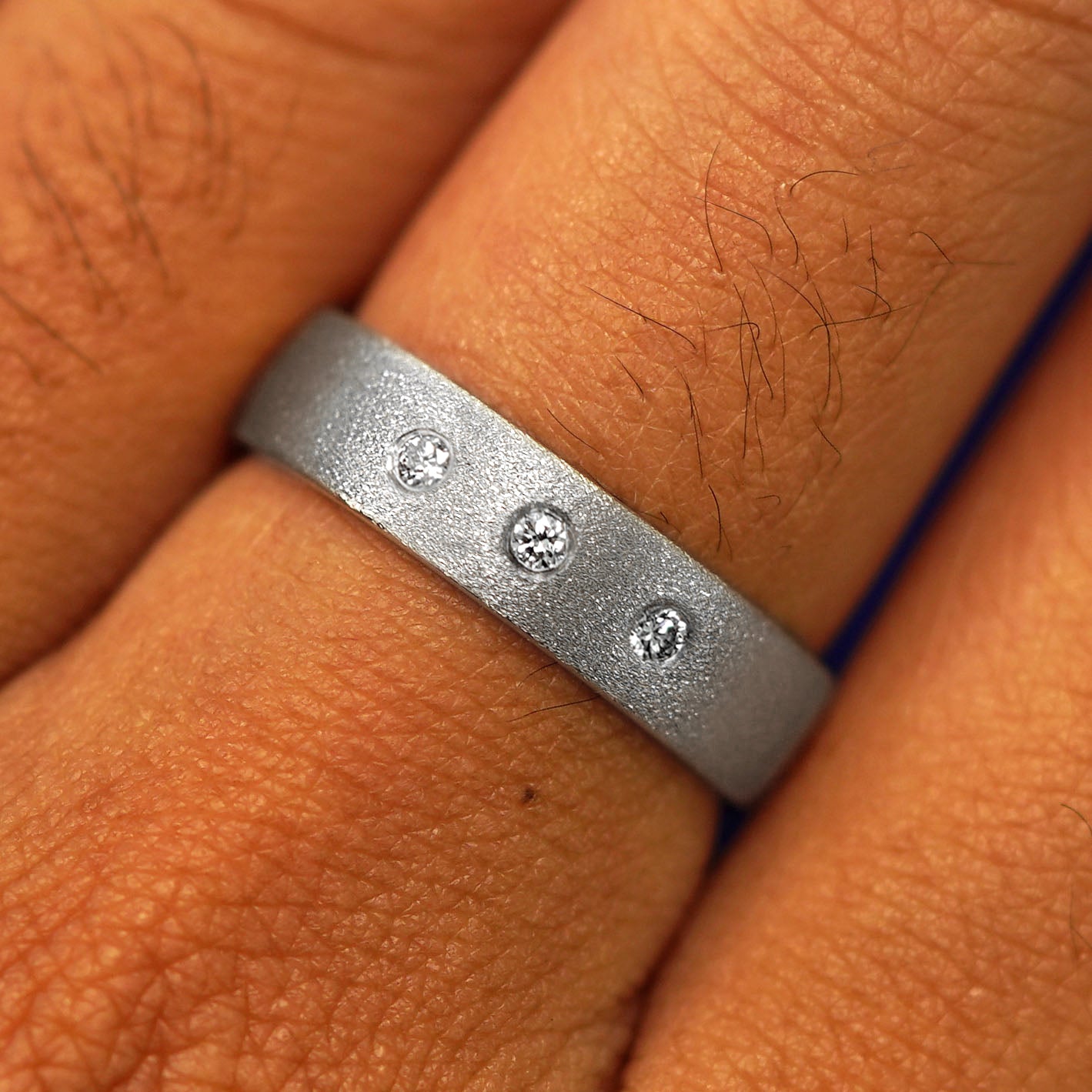 Close up view of a model's fingers wearing a Platinum Mix Stardust Band with three diamonds
