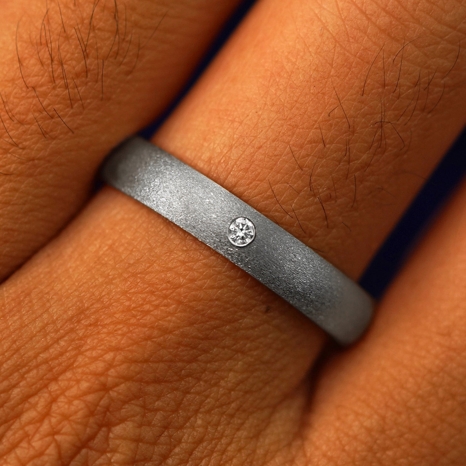 Close up view of a model's fingers wearing a 925 sterling silver Curvy Stardust Band with one diamond