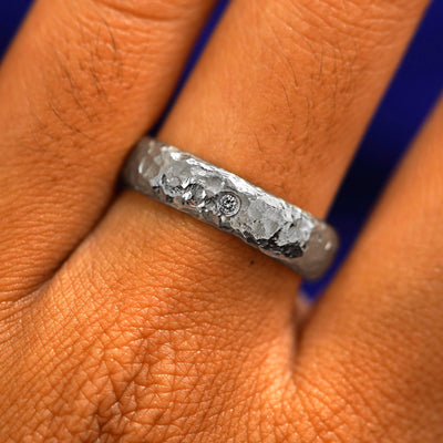Close up view of a model's fingers wearing a Platinum Mix Organic Band with one diamond