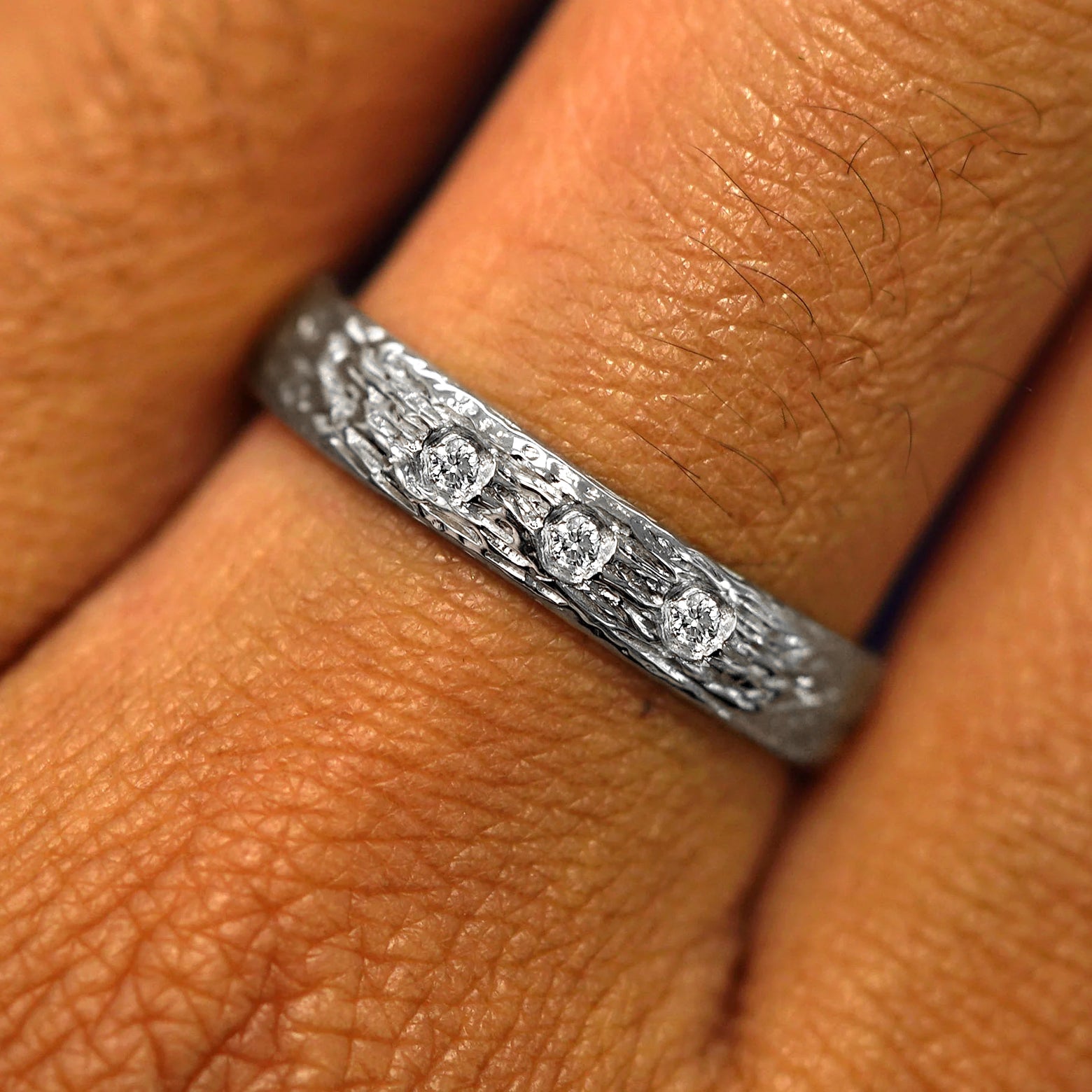 Close up view of a model's fingers wearing a Platinum Raw Band with three diamonds