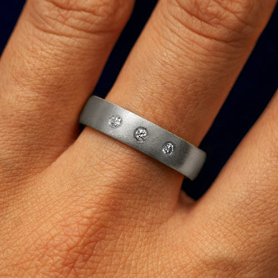 Close up view of a model's fingers wearing a Platinum Mix Matte Band with three diamonds