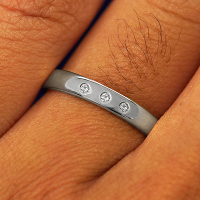 Close up view of a model's fingers wearing a Platinum Mix Mirror Band with three diamonds