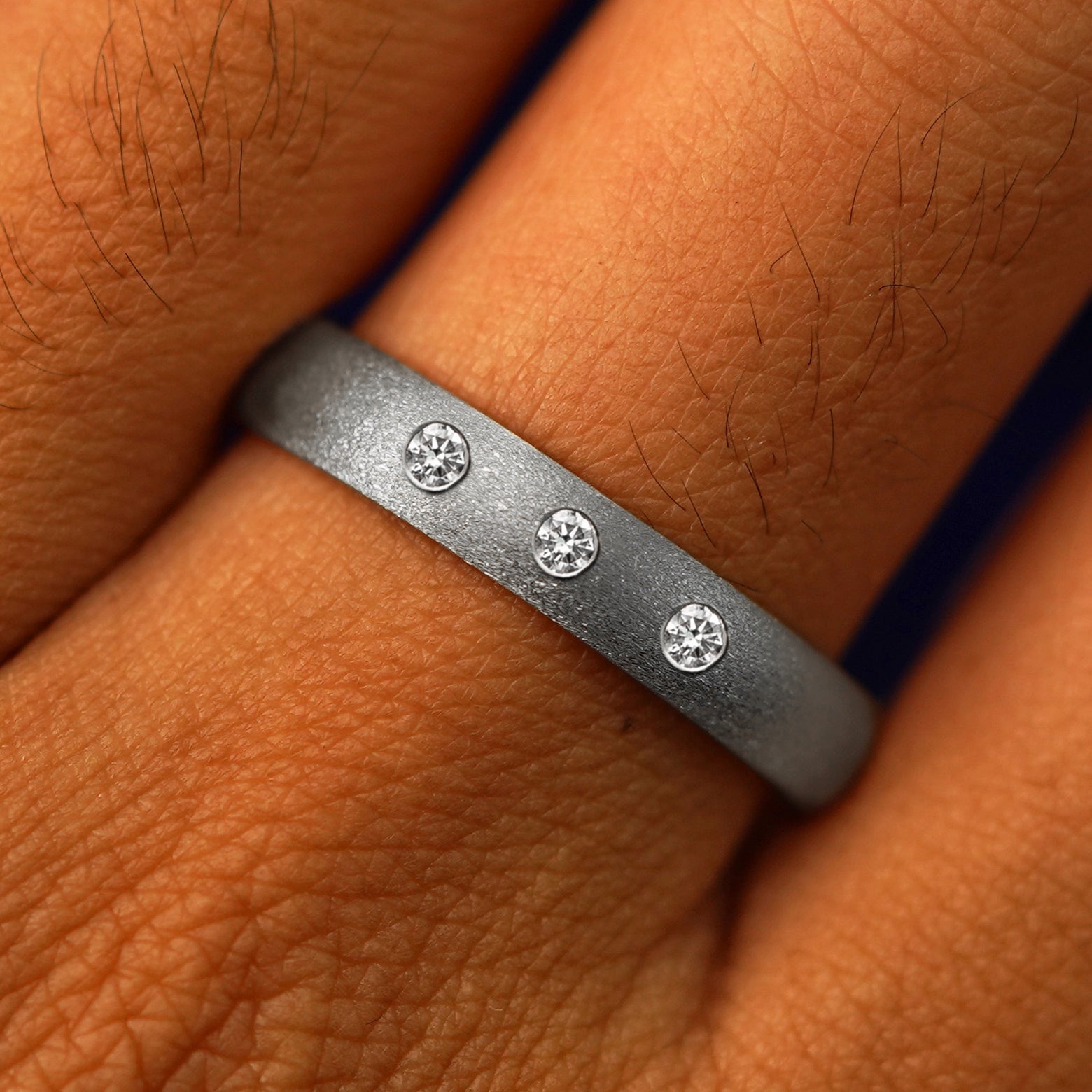 Close up view of a model's fingers wearing a 925 sterling silver Curvy Stardust Band with three diamonds