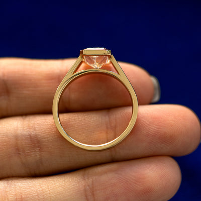 A yellow gold Radiant Cut Lab Diamond Cathedral Ring in a model's hand showing the thickness of the band