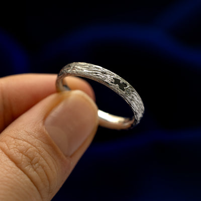 A model holding a black baguette diamond raw band tilted to show the details of the stone in the setting