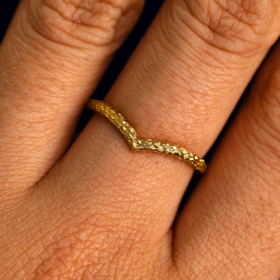 Close up view of a model's fingers wearing a 14k yellow gold raw finish Chevron Band